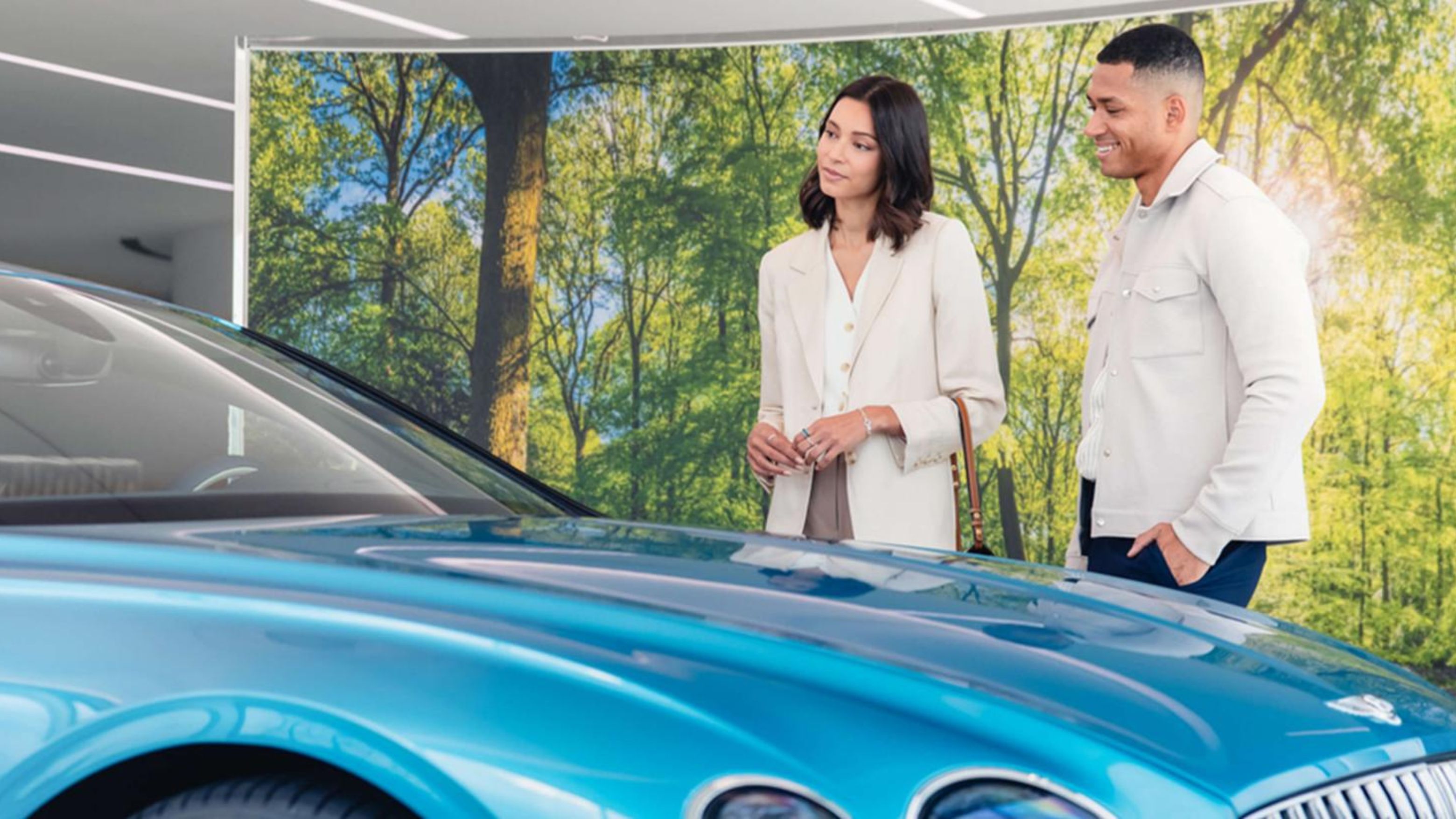 2 customers in showroom looking at Blue Bentley